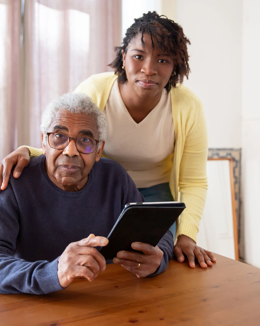 Resident and care professional viewing a tablet together in a living space.